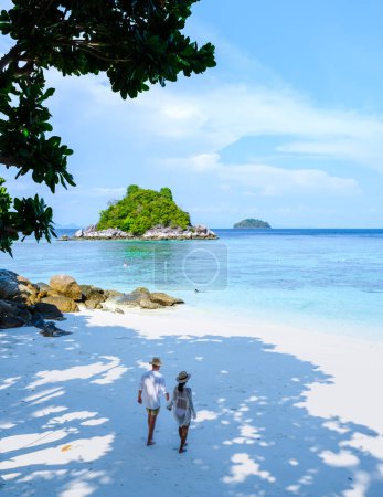Photo for A couple of men and women on vacation in Thailand walking at the beach, Koh Lipe Island Southern Thailand with turqouse colored ocean and white sandy beach at Ko Lipe - Royalty Free Image