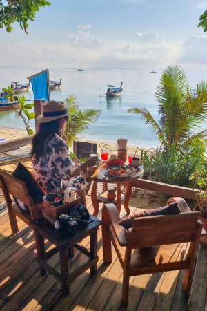 Foto de Mujer desayunando con café en la playa de Koh Lipe Island sur de Tailandia con turqouse color océano y playa de arena blanca en Ko Lipe. - Imagen libre de derechos