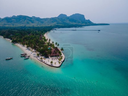 Téléchargez les photos : Koh Mook île tropicale dans la mer d'Andaman en Thaïlande, plage tropicale avec sable blanc et turqouse couleur océan avec cocotiers. bungalows en bois sur la plage - en image libre de droit