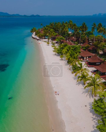 Photo for A couple of men and women on vacation at Koh Mook tropical Island in the Andaman Sea in Thailand, men and women walking on a beach with palm trees drone aerial view - Royalty Free Image