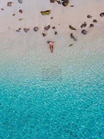 Photo for Women swimming in the ocean of Koh Kradan Island with a white tropical beach and turqouse colored ocean. women in blue ocean seen from above with a drone - Royalty Free Image