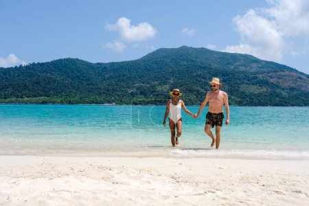 Téléchargez les photos : Couple sur la plage de Koh Lipe Island Thaïlande, une île tropicale avec un océan bleu et sable blanc doux. Ko Lipe Island Thaïlande. hommes et femmes se détendre sur la plage donnant sur l'océan - en image libre de droit