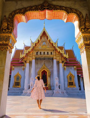Photo for A Asian woman walking at Wat Benchamabophit temple in Bangkok Thailand, The Marble temple in Bangkok. Asian woman with a hat visiting a temple in Bangkok - Royalty Free Image