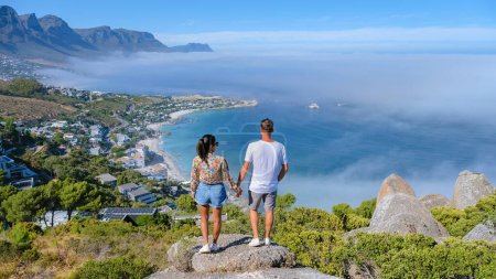 Foto de Pareja en el mirador The Rock en Cape Town Campsbay, vista sobre Camps Bay con niebla sobre el océano. niebla procedente del océano en Ciudad del Cabo Sudáfrica, hombres y mujeres en un mirador - Imagen libre de derechos