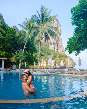 Téléchargez les photos : Couple d'hommes et de femmes à une piscine dans un complexe de luxe en Thaïlande pendant les vacances à Krabi - en image libre de droit