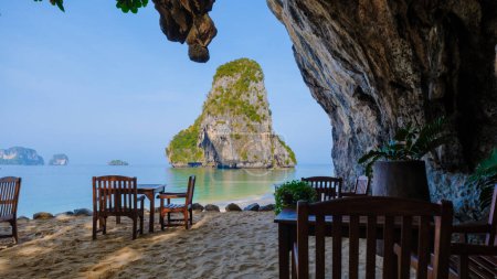Foto de Restaurante con sillas en la playa en una gruta de piedra caliza acantilado en Railai Beach Krabi Tailandia. - Imagen libre de derechos