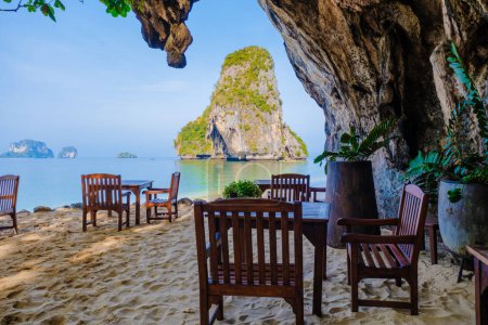 Foto de Restaurante con sillas en la playa en una gruta de piedra caliza acantilado en Railai Beach Krabi Tailandia en un día soleado en la playa de Phrangna - Imagen libre de derechos