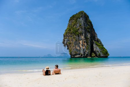 Téléchargez les photos : Un couple d'hommes et de femmes se détendre sur la plage pendant des vacances en Thaïlande Railay Beach Krabi par une journée ensoleillée - en image libre de droit
