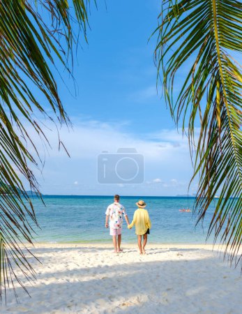 Téléchargez les photos : Un couple d'hommes et de femmes marchant sur la plage de l'île tropicale Koh Lipe sud de la Thaïlande. une plage de blanc tropical avec turqouse colorée océan coloré - en image libre de droit