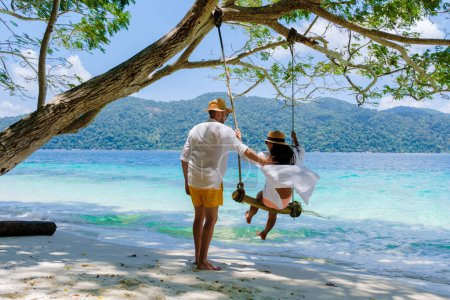 Photo for Couple playing at a rope swing on the beach of Ko Ra Wi Island Southern Thailand, tropical white sandy beach with turqouse colored ocean at Tarutao National Park, Koh Rawi, Tambon Ko Tarutao - Royalty Free Image