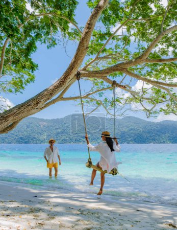 Photo for Couple playing at a rope swing on the beach of Ko Ra Wi Island Southern Thailand, tropical white sandy beach with turqouse colored ocean at Tarutao National Park, Koh Rawi, Tambon Ko Tarutao - Royalty Free Image