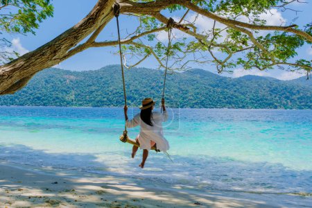 Photo for Women at a swing on the beach of Ko Ra Wi Island Southern Thailand, tropical white sandy beach with turqouse colored ocean at Tarutao National Park, Koh Rawi, Tambon Ko Tarutao - Royalty Free Image