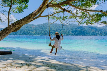 Photo for Women at a swing on the beach of Ko Ra Wi Island Southern Thailand, tropical white sandy beach with turqouse colored ocean at Tarutao National Park, Koh Rawi, Tambon Ko Tarutao - Royalty Free Image