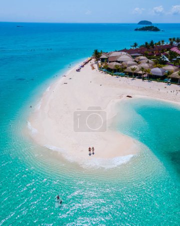Photo for Men and women walking on a sandbar in the ocean of Koh Lipe Southern Thailand during vacation. a couple at a sandbank in a turqouse colored ocean - Royalty Free Image