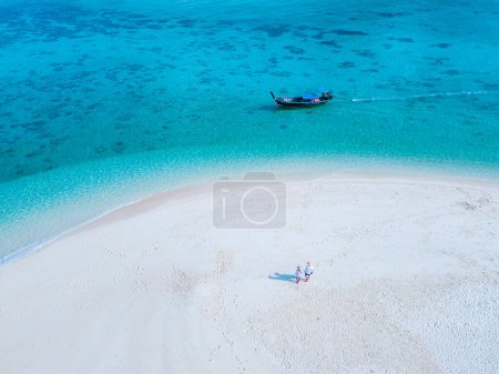 Foto de Hombres y mujeres caminando en un banco de arena en el océano de Koh Lipe Sur de Tailandia durante las vacaciones. una pareja en un banco de arena en un océano de color turquesa - Imagen libre de derechos