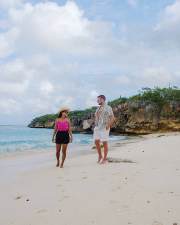 Foto de Grote Knip Beach Curacao Island, una playa tropical en la isla caribeña de Curazao Caribe. Un par de hombres y una mujer de vacaciones en Curazao están caminando por la playa - Imagen libre de derechos