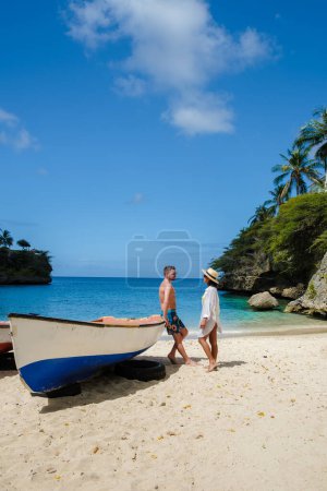 Photo for A couple of men and women at the beach of Playa Lagun Beach with a fishing boat at the Island of Curacao, Lagun Beach Curacao a small island in the Caribbean. - Royalty Free Image