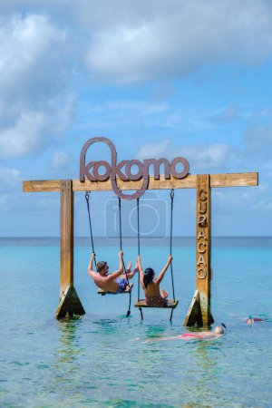 Téléchargez les photos : Couple à la balançoire dans l'océan de Curaçao île des Caraïbes, plage de Kokomo à l'île des Caraïbes de Curaçao - en image libre de droit