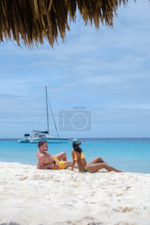 Téléchargez les photos : Un couple d'hommes et de femmes lors d'une excursion en bateau à petite île de Curaçao avec une plage blanche et turqouse couleur océan - en image libre de droit