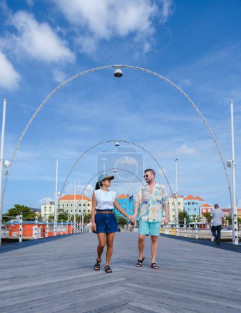 Téléchargez les photos : Willemstad Curaçao, bâtiments colorés autour de Willemstad Punda et Otrobanda, maisons multicolores Curaçao île des Caraïbes, couple d'hommes caucasiens et femme asiatique en vacances Curaçao. - en image libre de droit