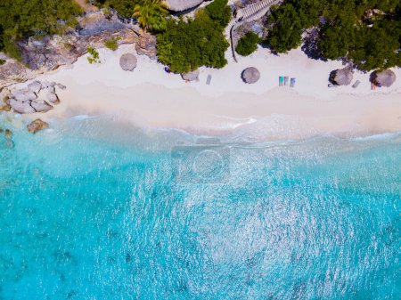 Téléchargez les photos : Playa Kalki Beach île caribéenne de Curaçao, Playa Kalki à Curaçao, plage de sable blanc avec une turque bleue couleur océan. Drone vue aérienne au-dessus d'une plage avec chaises longues et parasols - en image libre de droit