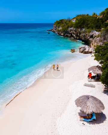 Téléchargez les photos : Playa Kalki Beach île caribéenne de Curaçao, Playa Kalki à Curaçao, plage de sable blanc avec une turque bleue couleur océan. Drone vue aérienne d'un couple d'hommes et de femmes à la plage - en image libre de droit