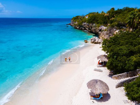 Téléchargez les photos : Playa Kalki à Curaçao, plage de sable blanc avec une turque bleue couleur océan. Drone vue aérienne d'un couple d'hommes et de femmes à la plage - en image libre de droit