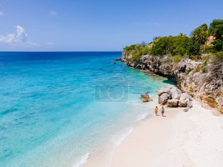 Playa Kalki in Curacao, white beach with a blue turqouse colored ocean. Drone aerial view of a couple of men and women at the beach
