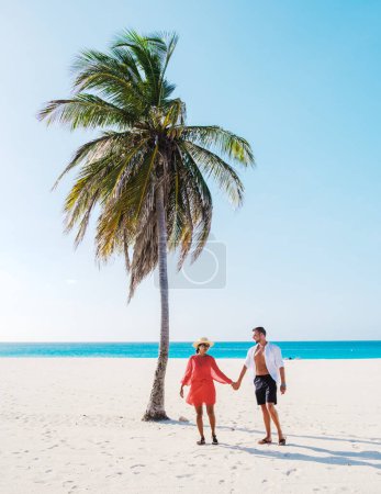 Foto de Palm Beach Aruba Caribbean, un par de hombres y mujeres en una larga playa de arena blanca con palmeras en las Antillas de Aruba. - Imagen libre de derechos
