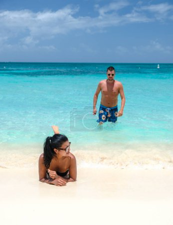 Foto de Palm Beach Aruba Caribbean, un par de hombres y mujeres en una larga playa de arena blanca con palmeras en las Antillas de Aruba relajándose en el océano de color turquesa - Imagen libre de derechos