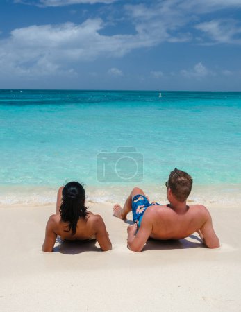 Foto de Palm Beach Aruba Caribbean, un par de hombres y mujeres en una larga playa de arena blanca con palmeras en las Antillas de Aruba relajándose en el océano de color turquesa - Imagen libre de derechos