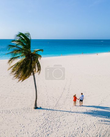 Photo for Eagle Beach Aruba, Palm Trees on the shoreline of Eagle Beach in Aruba, a couple of man, and woman on the beach of Aruba - Royalty Free Image