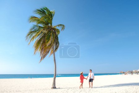 Téléchargez les photos : Eagle Beach Aruba, Palmiers sur le rivage d'Eagle Beach à Aruba, un couple d'hommes et de femmes sur la plage d'Aruba - en image libre de droit