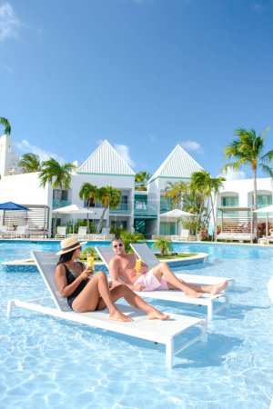 Téléchargez les photos : Resort de luxe avec piscine près de Palm Beach Aruba Caraïbes, couple homme et femme d'âge moyen en vacances de luxe dans les Caraïbes pendant l'été - en image libre de droit