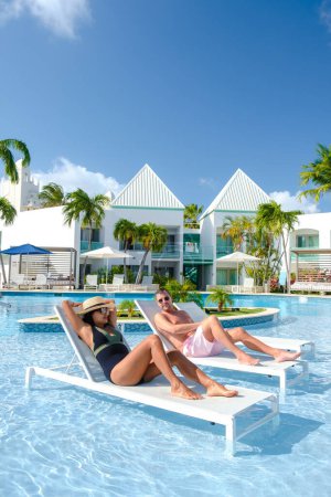 Téléchargez les photos : Resort de luxe avec piscine près de Palm Beach Aruba Caraïbes, couple homme et femme d'âge moyen en vacances de luxe dans les Caraïbes - en image libre de droit