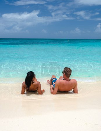 Foto de Palm Beach Aruba Caribbean, un par de hombres y mujeres en una larga playa de arena blanca con palmeras en las Antillas de Aruba con un océano de color turquesa - Imagen libre de derechos