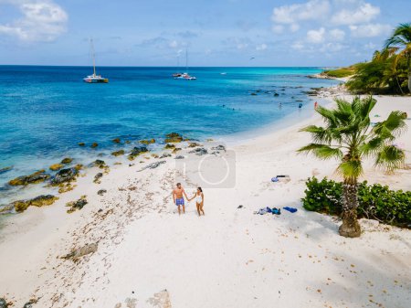 Téléchargez les photos : Eagle Beach Aruba, Palmiers sur le rivage d'Eagle Beach à Aruba, quelques hommes, et une femme sur la plage d'Aruba - en image libre de droit