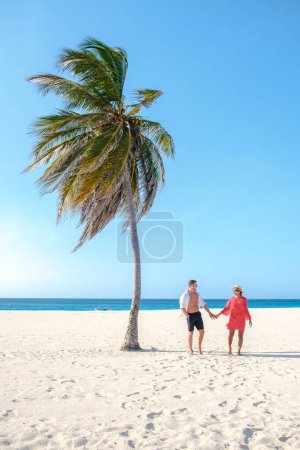 Photo for Eagle Beach Aruba, Palm Trees on the shoreline of Eagle Beach in Aruba, a couple of men, and a woman on the beach of Aruba - Royalty Free Image