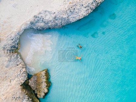 Photo for A couple of men and women on the beach of Tres Trap Aruba Caribbean Island. Tres Trapi Bay is popular with locals for snorkeling and diving in the turqouse colored ocean - Royalty Free Image