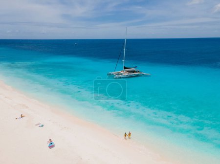 Téléchargez les photos : Un couple d'hommes et de femmes sur une excursion en bateau à petite île de Curaçao avec une plage blanche et turqouse couleur océan par une journée ensoleillée - en image libre de droit