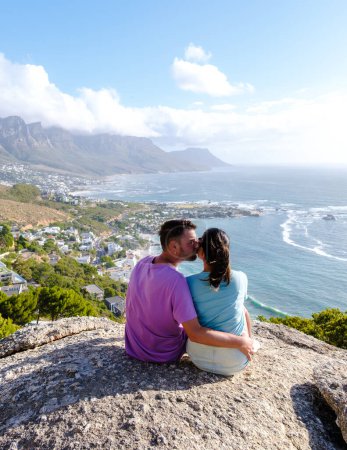 Photo for A couple of men and women at the The Rock viewpoint in Cape Town over Campsbay, view over Camps Bay with fog over the ocean. fog coming in from the ocean at Camps Bay Cape Town South Africa - Royalty Free Image