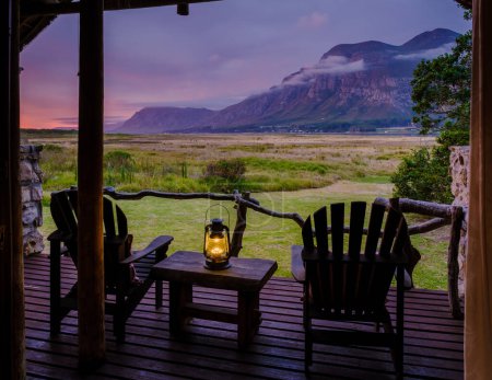 Photo for Mountains and grassland near Hermanus at the Garden Route Western Cape South Africa Whale coast. A lodge wooden bungalow with chairs during a vacation in South Africa at Susnet - Royalty Free Image