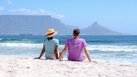 Foto de Bloubergstrand Ciudad del Cabo Sudáfrica en un brillante día de verano, la playa de Blouberg, con arena blanca y suave polvo, y el océano azul. pareja en la playa, hombres y mujeres relajándose en la playa - Imagen libre de derechos