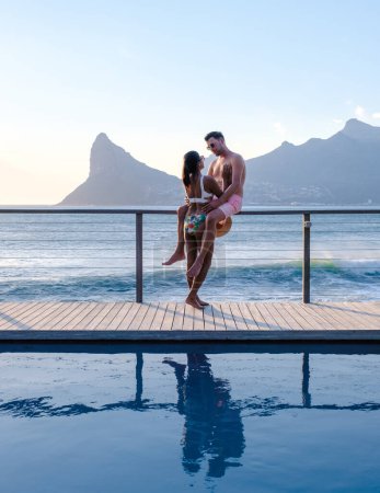 Photo for Couple man and women in front of Infinity pool looking out over the ocean of Cape Town South Africa, man and woman in a swimming pool during vacation - Royalty Free Image