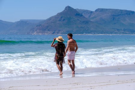 Photo for Kommetjie Public Beach Cape Town South Africa, white beach and blue ocean at Kommetjie on a summer day, couple man and woman walking at the beach in Cape Town South Africa - Royalty Free Image
