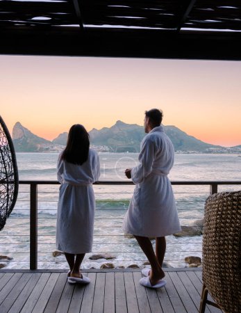 Photo for Couple man and women drinking coffee in the morning during sunrise on the balcony at vacation in Cape Town South Africa. - Royalty Free Image