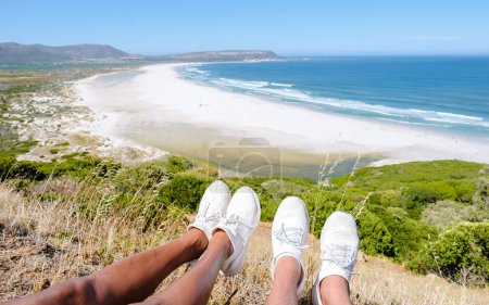 Foto de Hermosa playa de arena blanca Noordhoek a lo largo de Chapmans pico en coche Ciudad del Cabo Sudáfrica. Noordhoek Beach Ciudad del Cabo. Pies de hombre y mujer al borde de una playa - Imagen libre de derechos