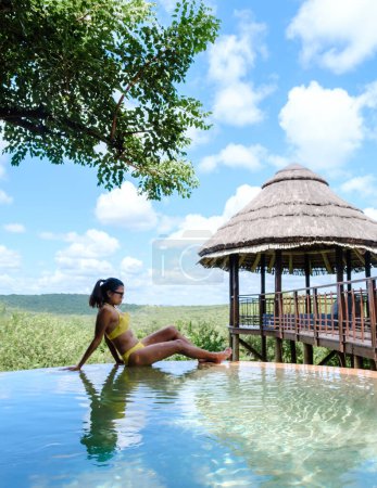 Téléchargez les photos : Femme au bord de la piscine lors d'un safari de luxe, Afrique du Sud, un lodge de safari de luxe dans la brousse d'une réserve de gibier - en image libre de droit