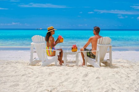 Foto de Pareja de hombres y mujeres en la playa con una bebida de coco Praslin Seychelles isla tropical con playas blancas y palmeras, la playa de Anse Volbert Seychelles. - Imagen libre de derechos