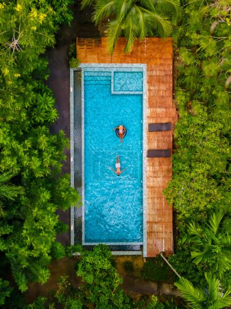 Téléchargez les photos : Couple d'hommes et de femmes dans une piscine dans la jungle de Krabi Thaïlande, vue aérienne avec un drone au-dessus de la piscine dans la jungle de Thaïlande. - en image libre de droit